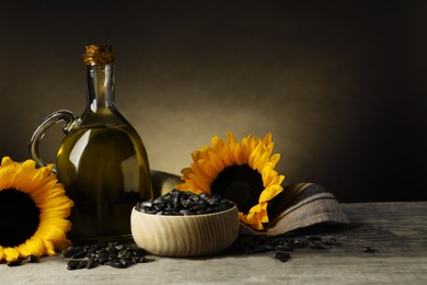 Sunflower cooking oil, seeds and yellow flowers on light grey table, space for text