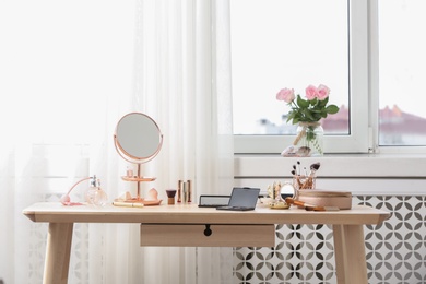 Photo of Dressing table with different makeup products and accessories in room interior