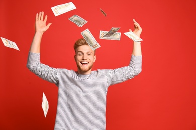Photo of Portrait of happy lottery winner under money rain on red background