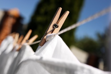 Clean clothes drying outdoors, closeup. Focus on clothespin