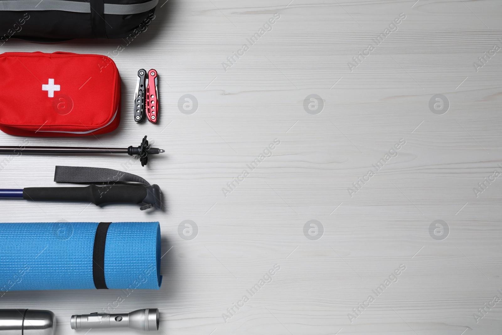 Photo of Flat lay composition with trekking poles and other hiking equipment on white wooden background, space for text