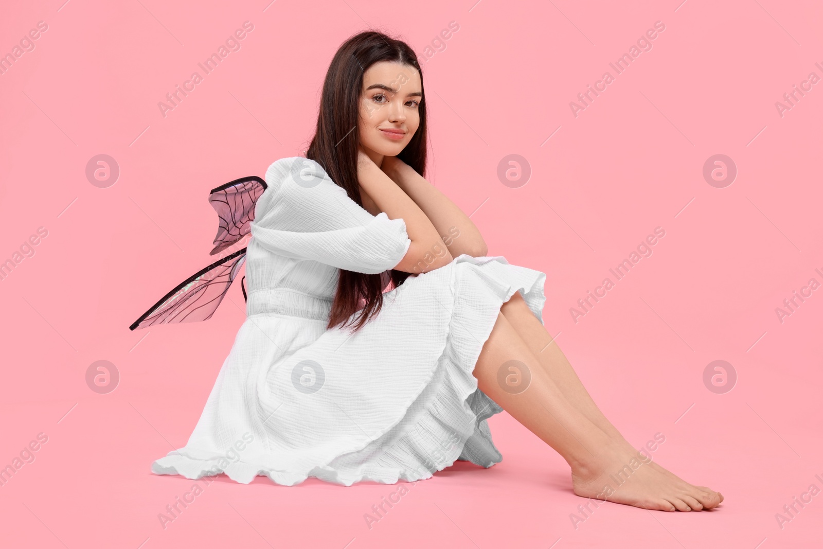 Photo of Beautiful girl in fairy costume with wings on pink background