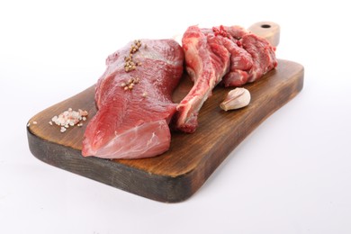 Board with pieces of raw beef meat and spices isolated on white