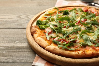 Photo of Board with delicious vegetarian pizza on wooden table, closeup. Space for text