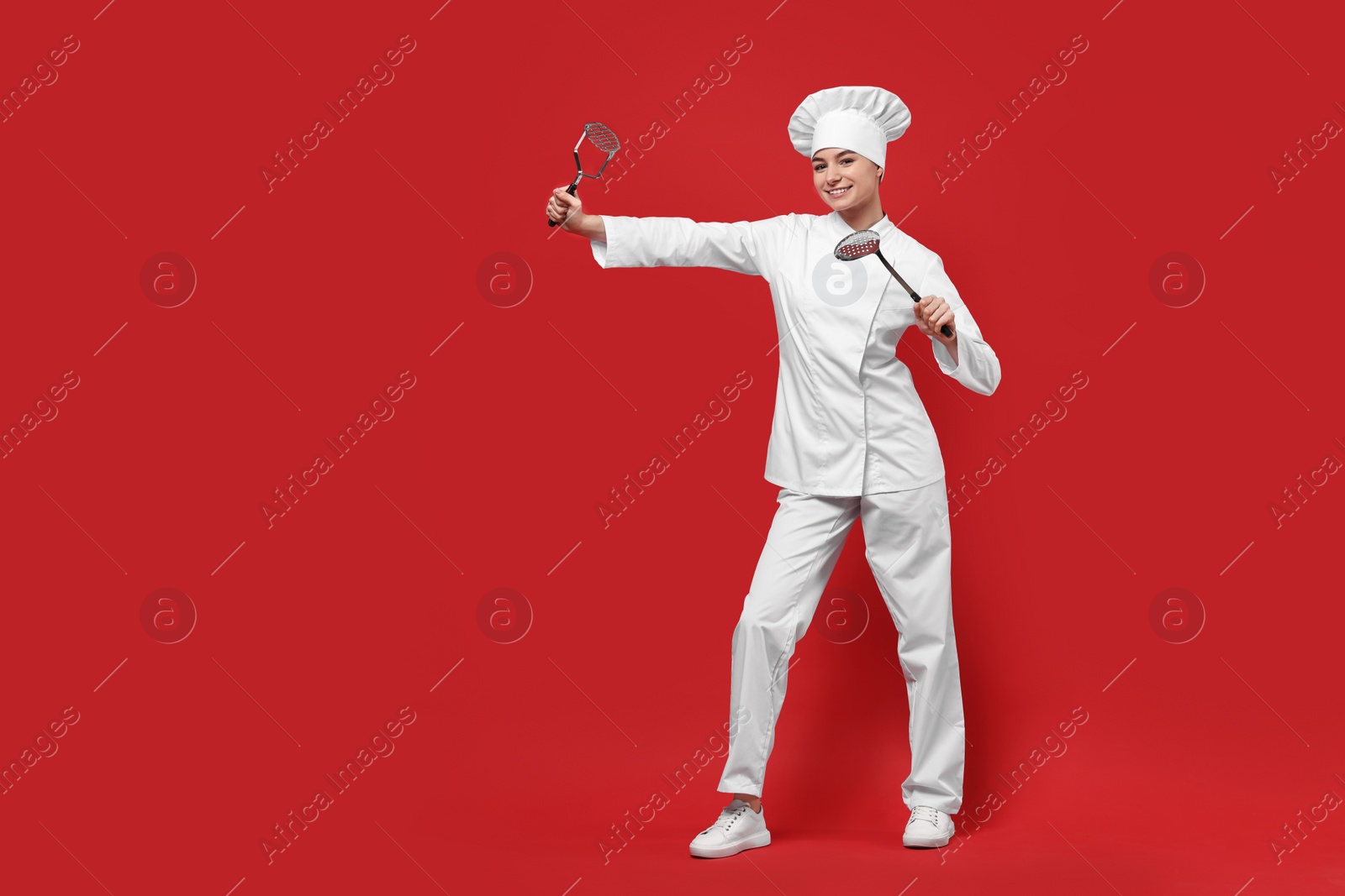 Photo of Professional chef with potato pusher and skimmer having fun on red background