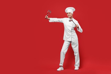 Photo of Professional chef with potato pusher and skimmer having fun on red background