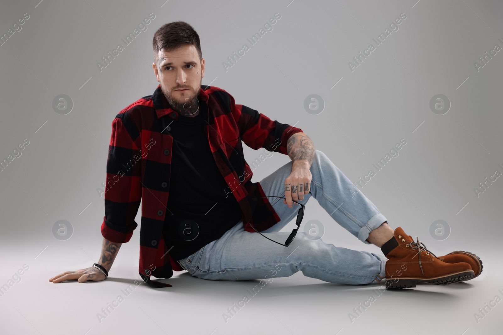 Photo of Handsome hipster man sitting on light grey background