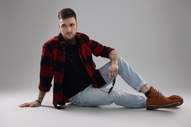 Handsome hipster man sitting on light grey background