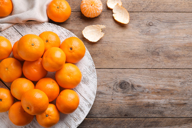 Photo of Fresh ripe tangerines on wooden table, flat lay. Space for text