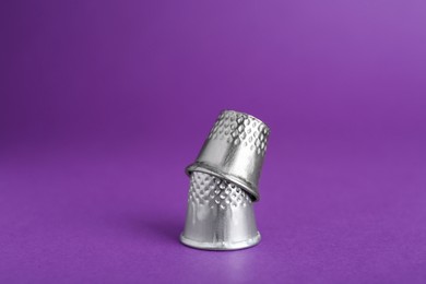 Sewing thimbles on purple background, closeup. Space for text