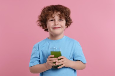 Photo of Cute little boy with glass of fresh juice on pink background