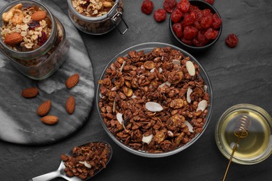Photo of Tasty granola served with nuts and dry fruits on black table, flat lay