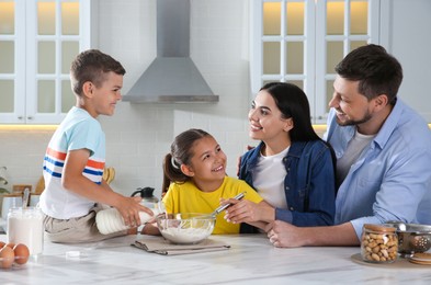 Happy family cooking together at table in kitchen. Adoption concept