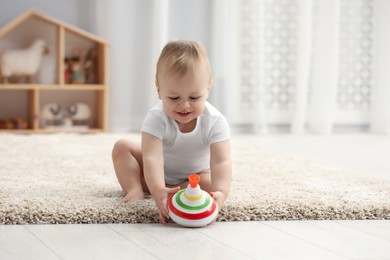 Children toys. Cute little boy playing with spinning top on rug at home