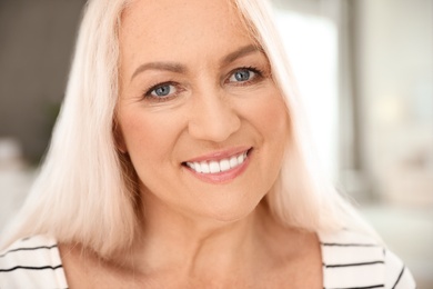 Portrait of mature woman with beautiful face on blurred background, closeup view