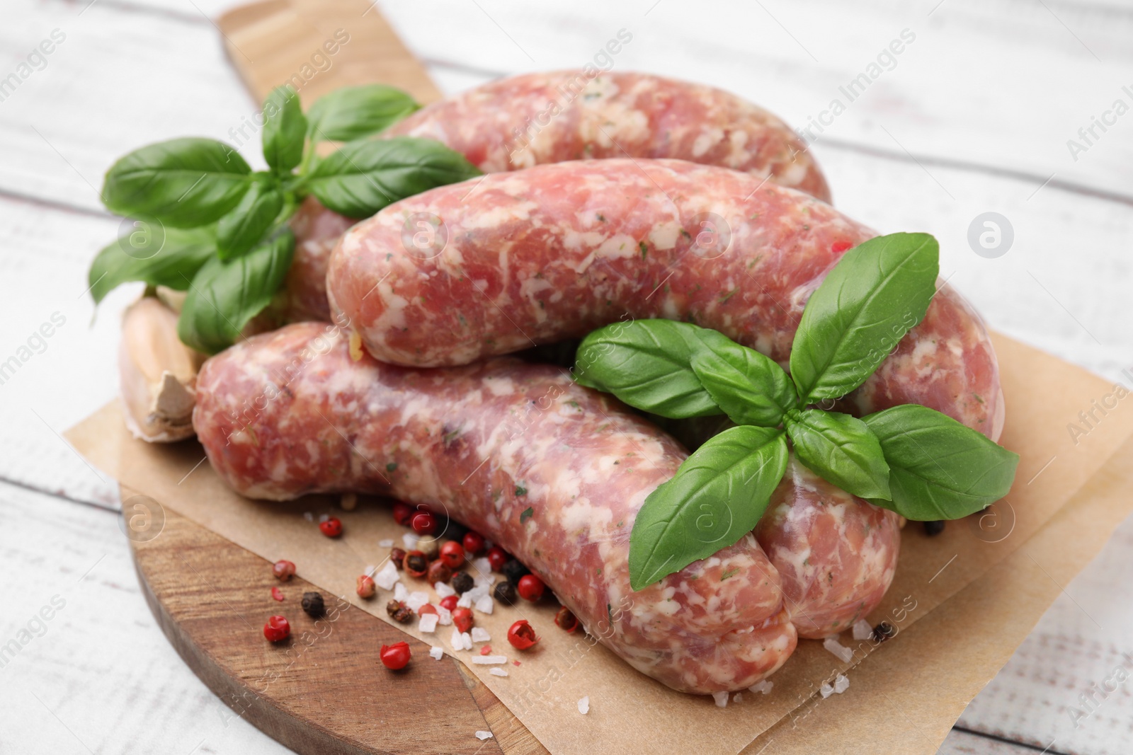 Photo of Raw homemade sausages and different spices on white wooden table, closeup