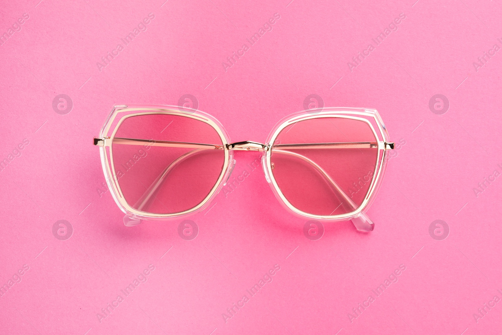 Photo of New stylish sunglasses on pink background, top view