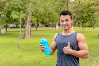 Photo of Man with bottle of protein shake in park. Space for text