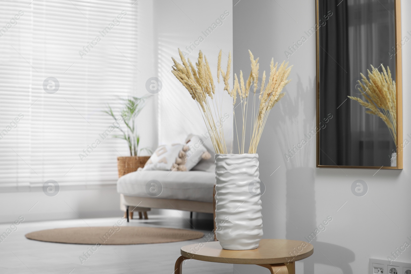 Photo of Stylish vase with dry decorative spikes on wooden table indoors