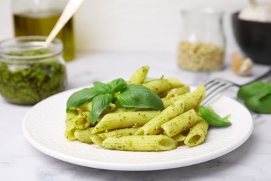 Photo of Delicious pasta with pesto sauce and basil on white marble table, closeup