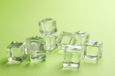 Photo of Crystal clear ice cubes on light green background