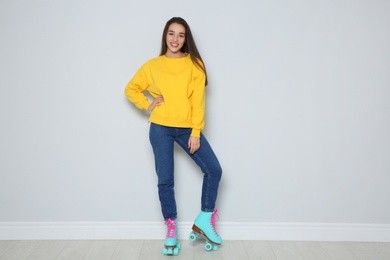 Full length portrait of young woman with roller skates near color wall