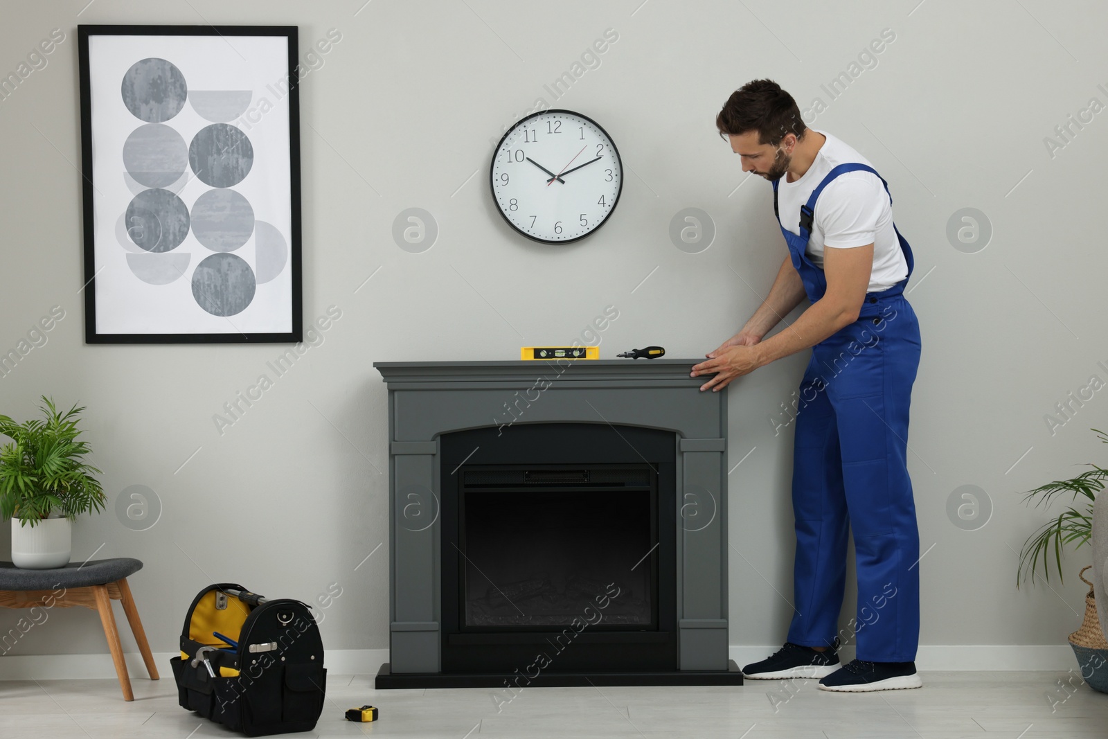 Photo of Professional technician installing electric fireplace in room