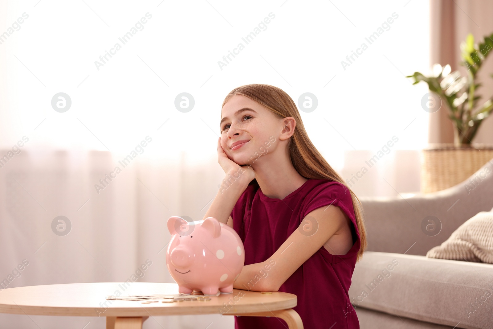 Photo of Teen girl with piggy bank and money at home