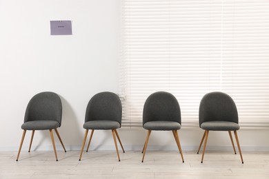 Many chairs near white wall in waiting area indoors