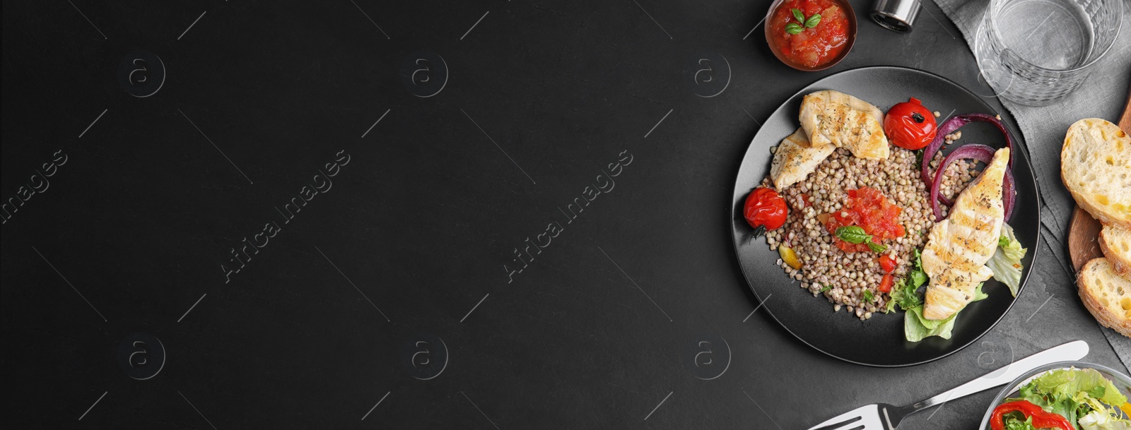 Image of Tasty buckwheat porridge with meat, vegetables and space for text on black table, flat lay. Banner design