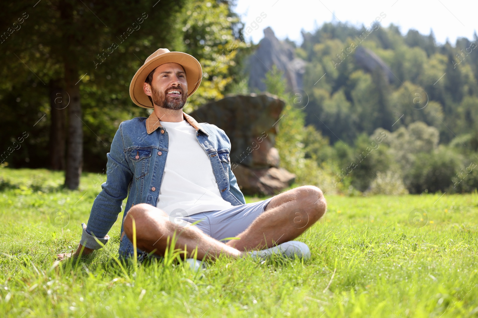 Photo of Feeling freedom. Smiling man enjoying nature on green grass outdoors