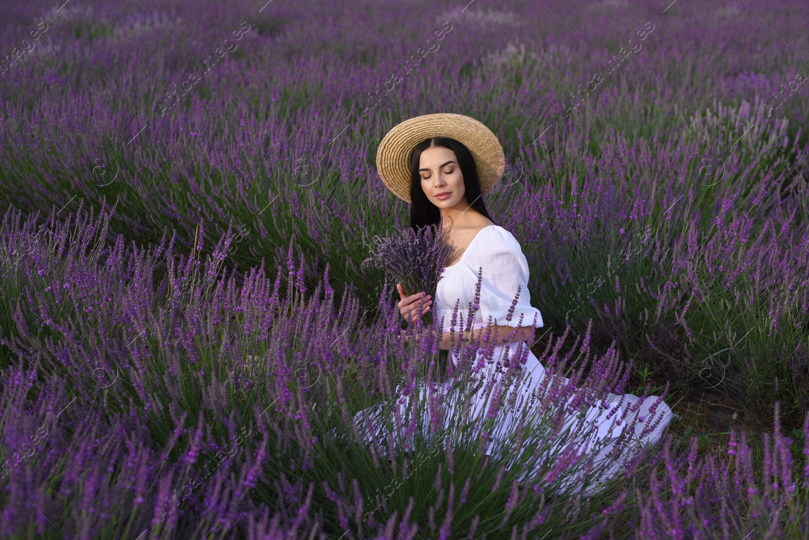 Photo of Beautiful young woman sitting in lavender field