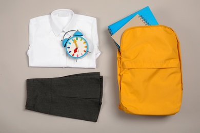 School uniform for girl and backpack on grey background, top view