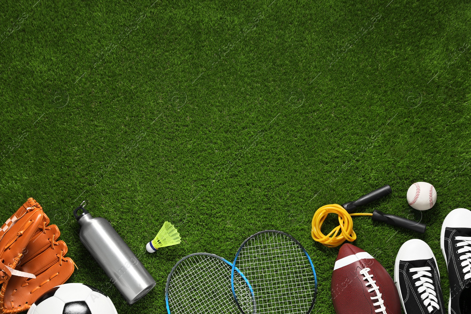 Photo of Different sports equipment on green grass, flat lay. Space for text