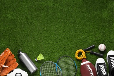 Photo of Different sports equipment on green grass, flat lay. Space for text