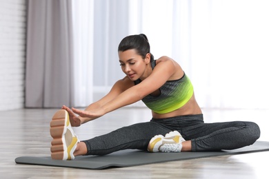 Young woman in fitness clothes doing exercise at home