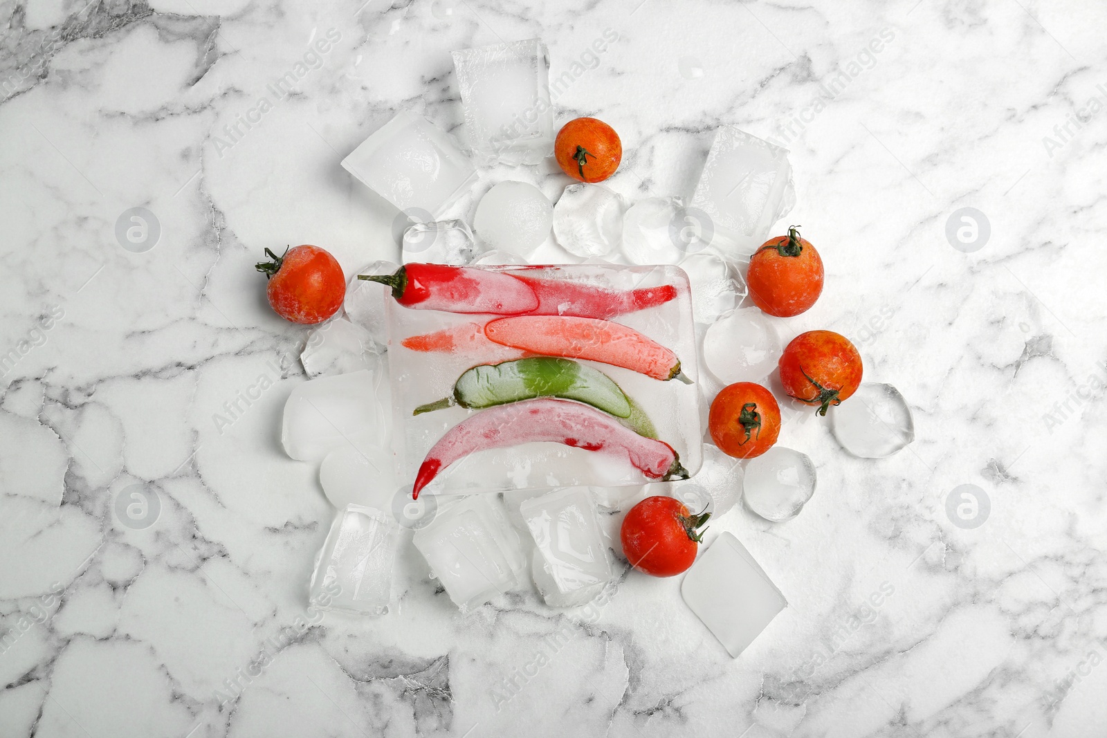 Photo of Frozen vegetables and ice cubes on marble table, top view