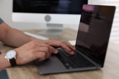 Programmer working with laptop at desk in office, closeup