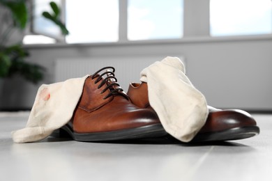 Photo of Stylish shoes with dirty socks on white wooden floor indoors, closeup