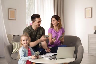 Happy family counting money on sofa at home