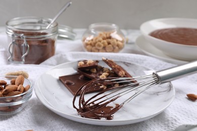 Whisk with chocolate cream and ingredients on table