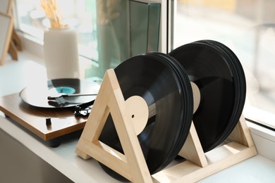 Vinyl records and player on white windowsill indoors