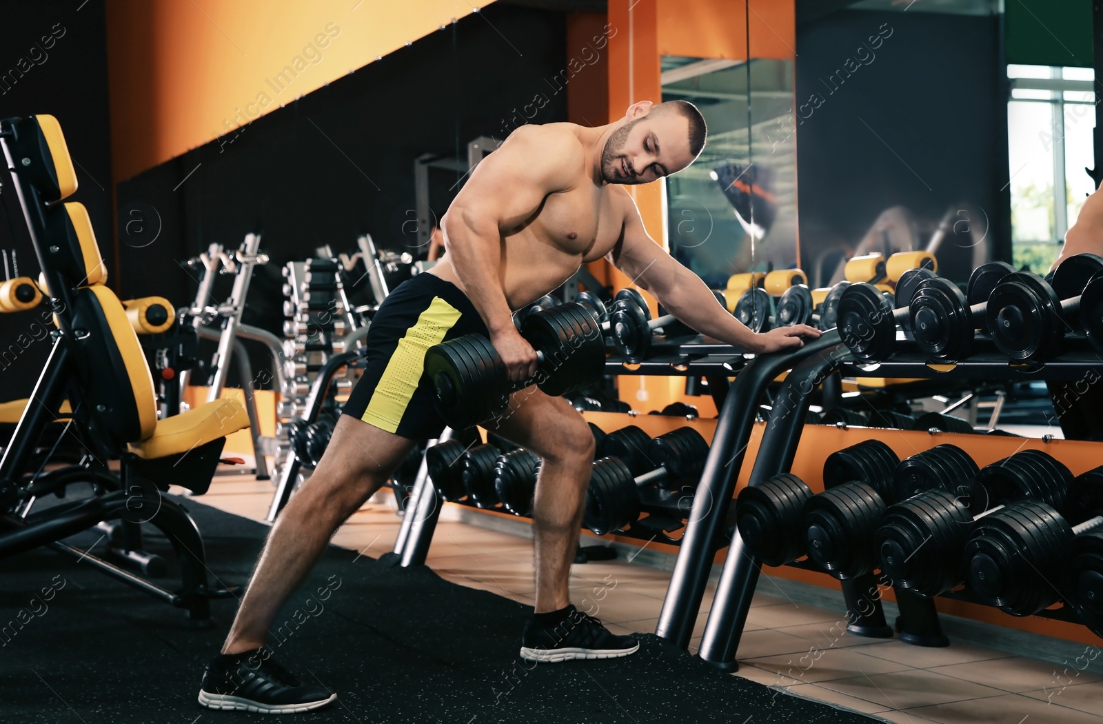 Photo of Strong young man lifting dumbbell in gym