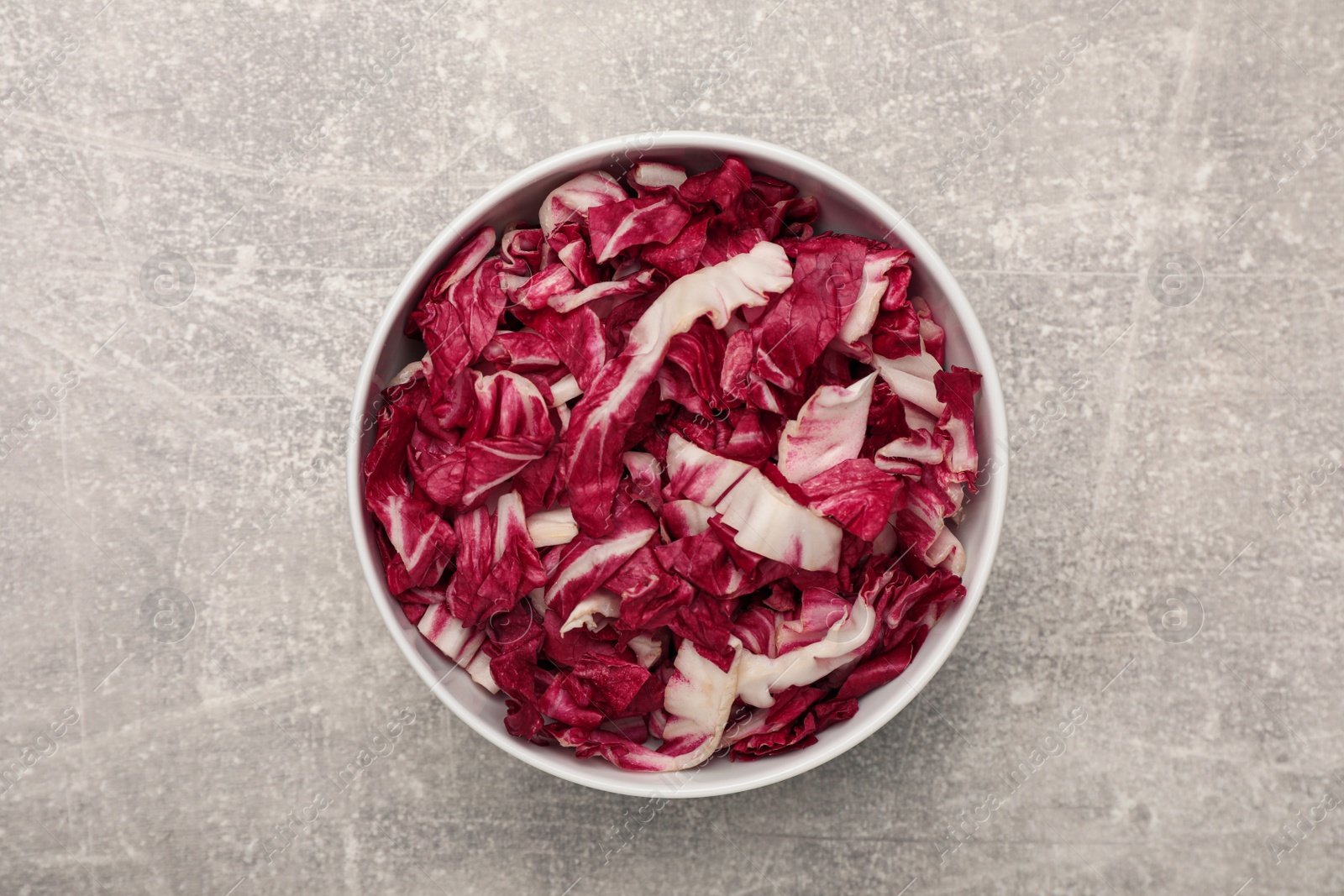 Photo of Cut radicchio in bowl on grey table, top view
