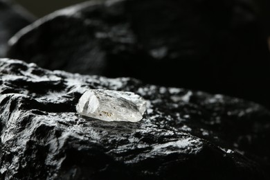 Photo of Shiny rough diamond on stone surface. Space for text