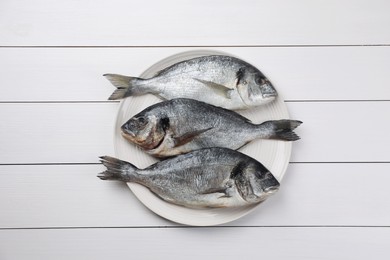 Photo of Fresh raw dorado fish on white wooden table, top view