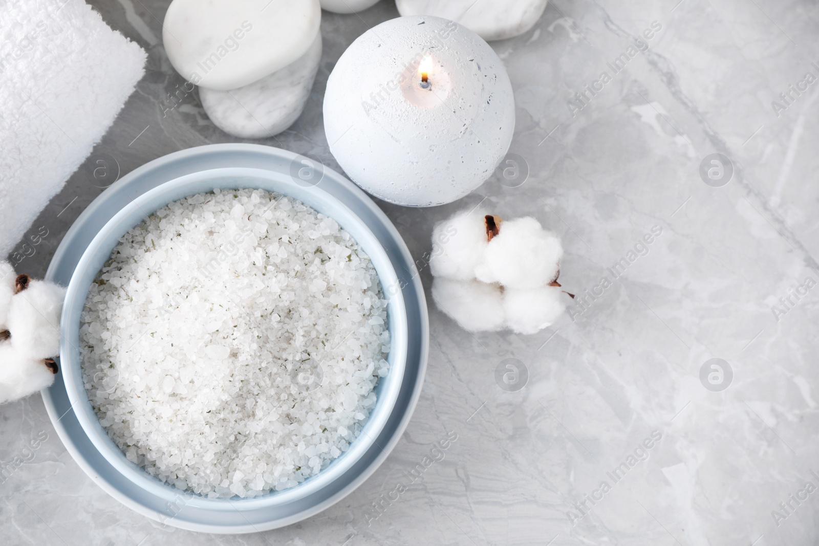 Photo of White sea salt and supplies for spa scrubbing procedure on grey marble table, flat lay