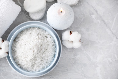 Photo of White sea salt and supplies for spa scrubbing procedure on grey marble table, flat lay