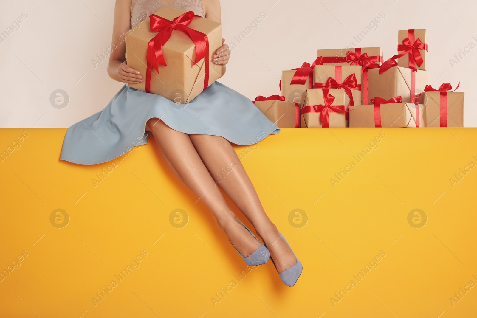 Photo of Woman with gift boxes sitting on yellow background, closeup. Black Friday