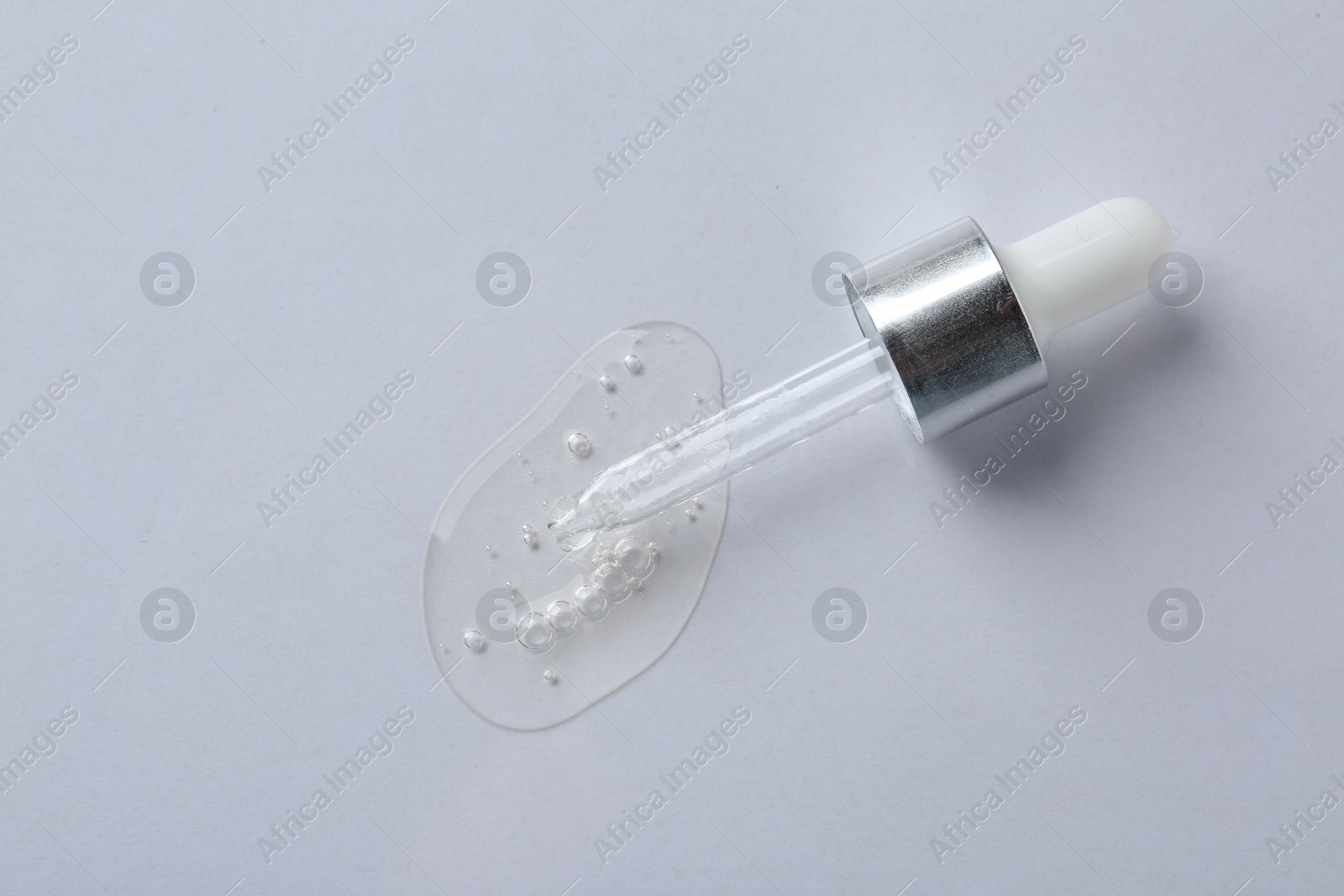 Photo of Pipette with cosmetic serum on white background, top view